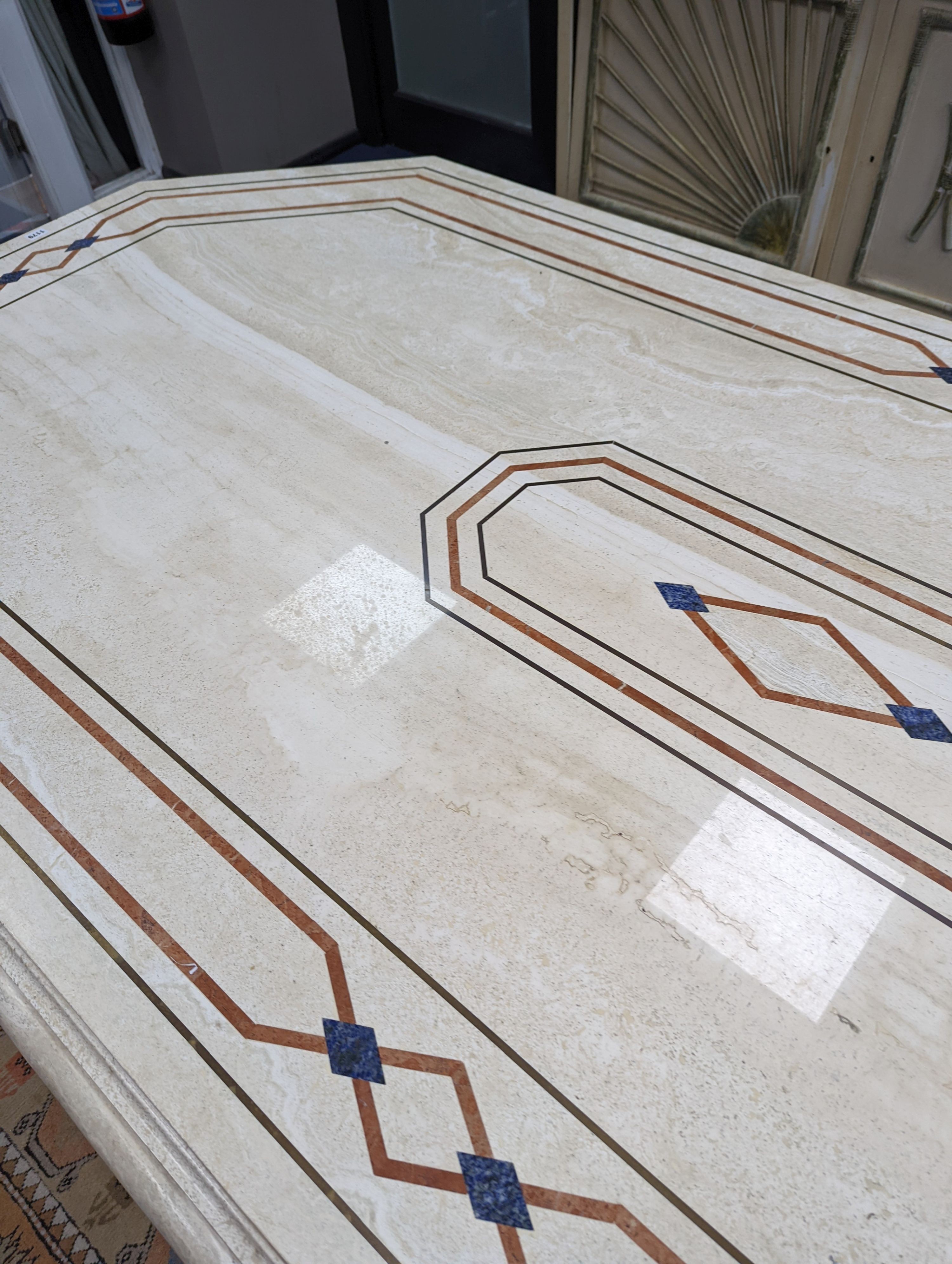 A Travertine marble dining table of elongated ocgtagonal form on twin octagonal column supports, length 260cm, depth 120cm, height 74cm